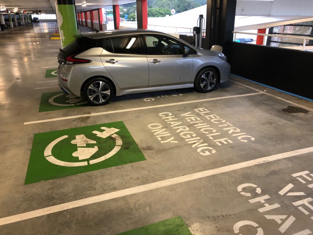 Nissan Leaf being charged at a public charging station in a shopping centre carpark