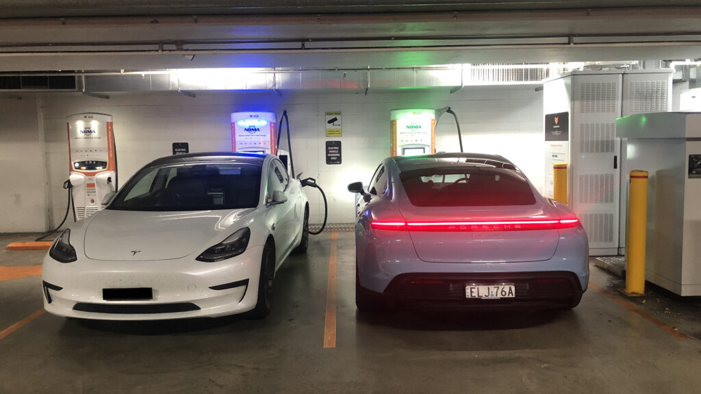 Porsche Taycan 4S charging on a 350kW ultra-rapid charger alongside a Tesla Model 3