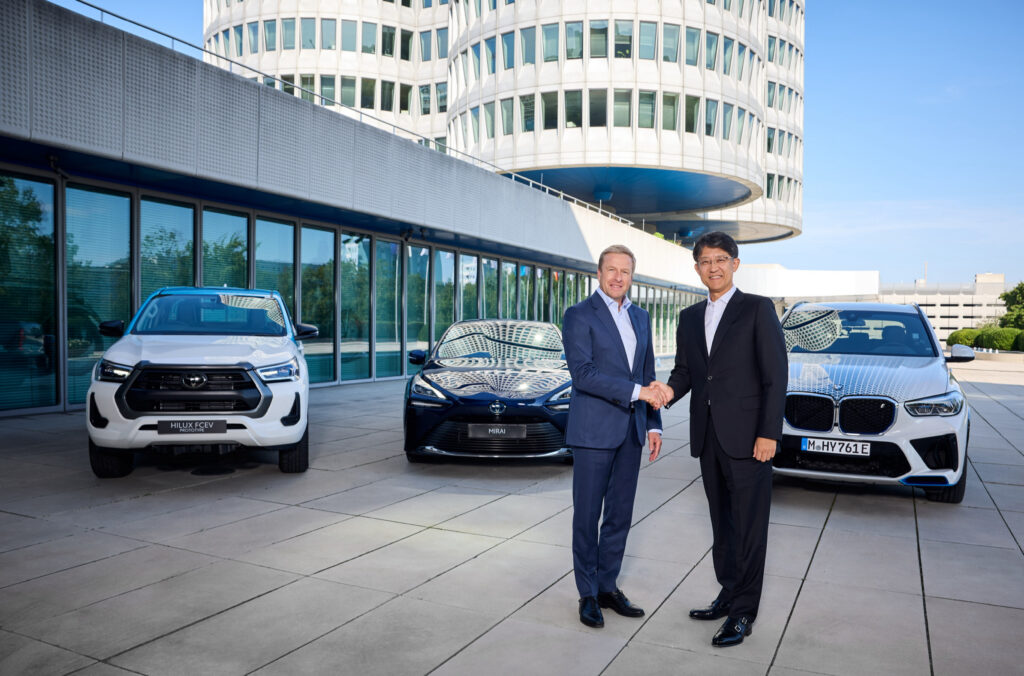 Toyota president Koji Sato and BMW chairman Oliver Zipse at BMW’s headquarters in Munich to announce an increased collaboration on the development of fuel cell electric vehicle technology. Behind them is a Toyota Hilux FCEV prototype, Toyota Mirai and BMW iX5 FCEV development vehicle.